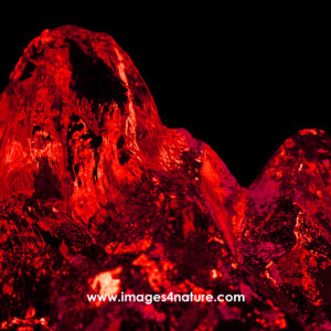 Close-up on iceberg peak illuminated with vibrant red light