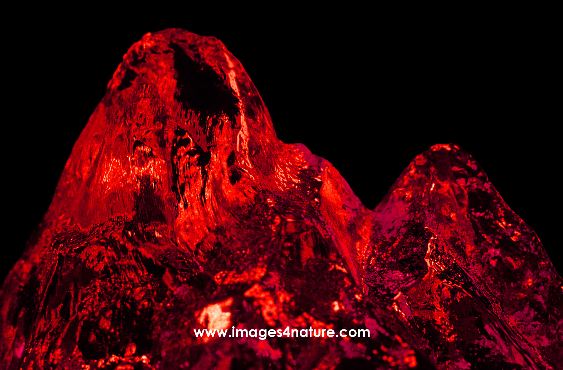 Close-up on iceberg peak illuminated with vibrant red light