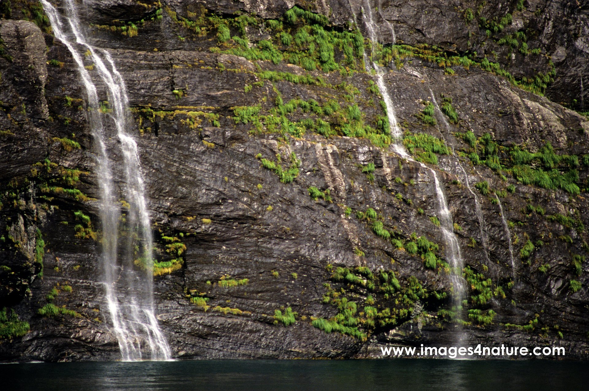 Tiny waterfalls running down steep rocks into Geiranger fjord