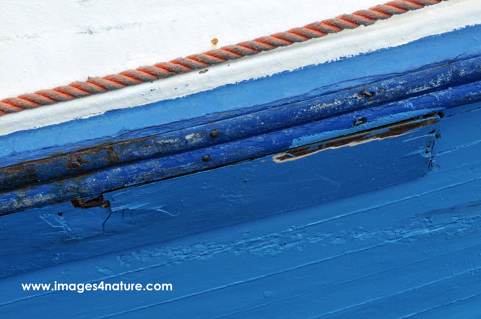 Close up wooden boat painted blue and white with orange rope