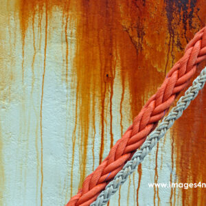 Two ropes against weathered rusty painted ship wall