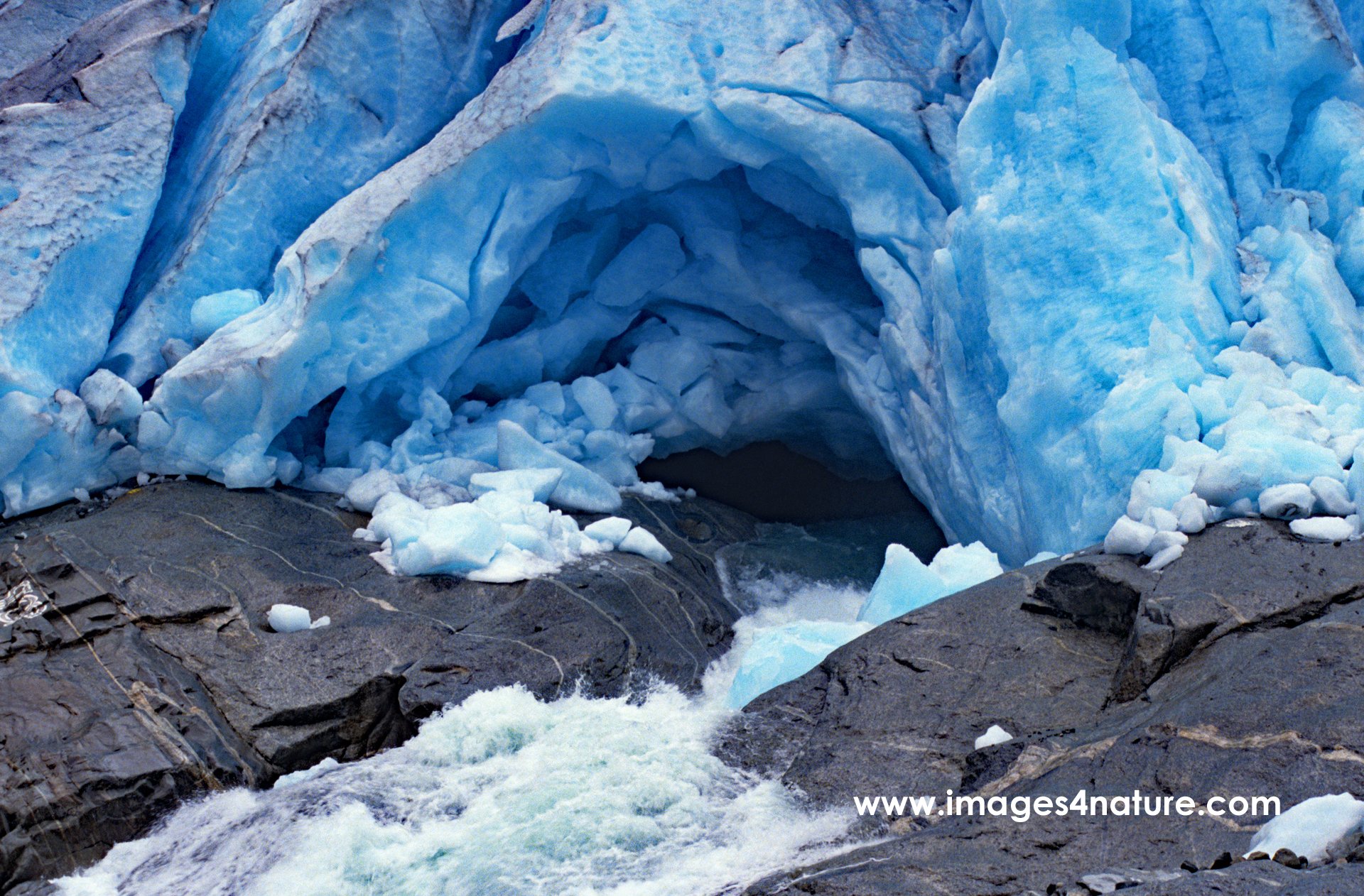Stream emerging from bluish glacier ice on rock surface