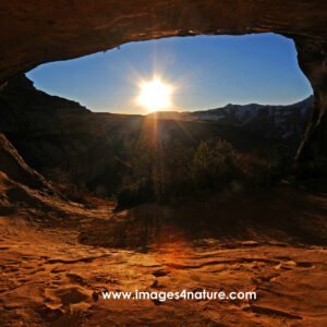 Breathtaking view below red sandstone arch cave against sunset