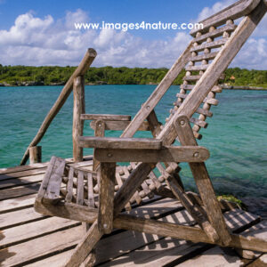Wooden deck with weathered lounge chair at a tropical lagoon