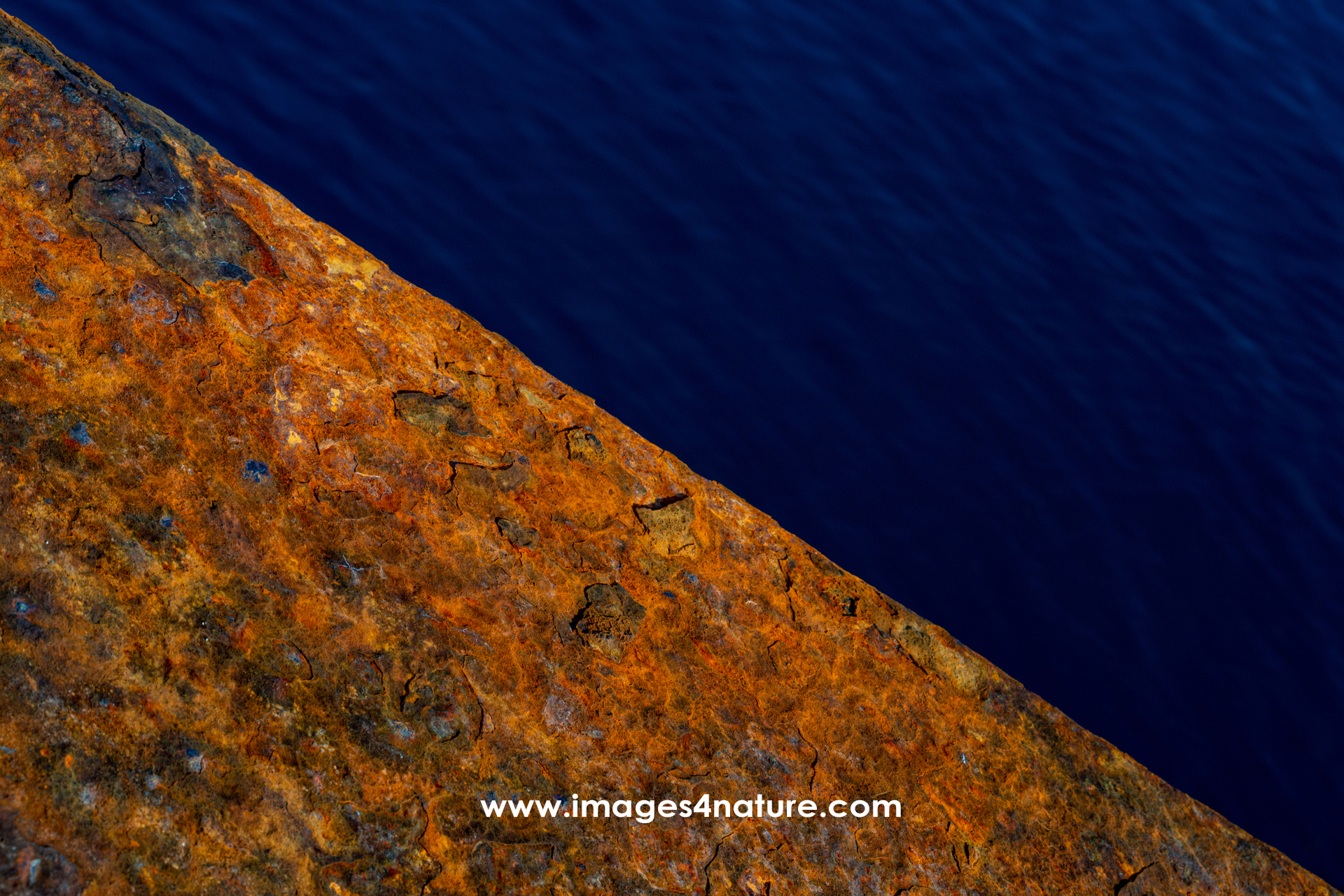 Diagonal close-up of rusted metal against dark blue water
