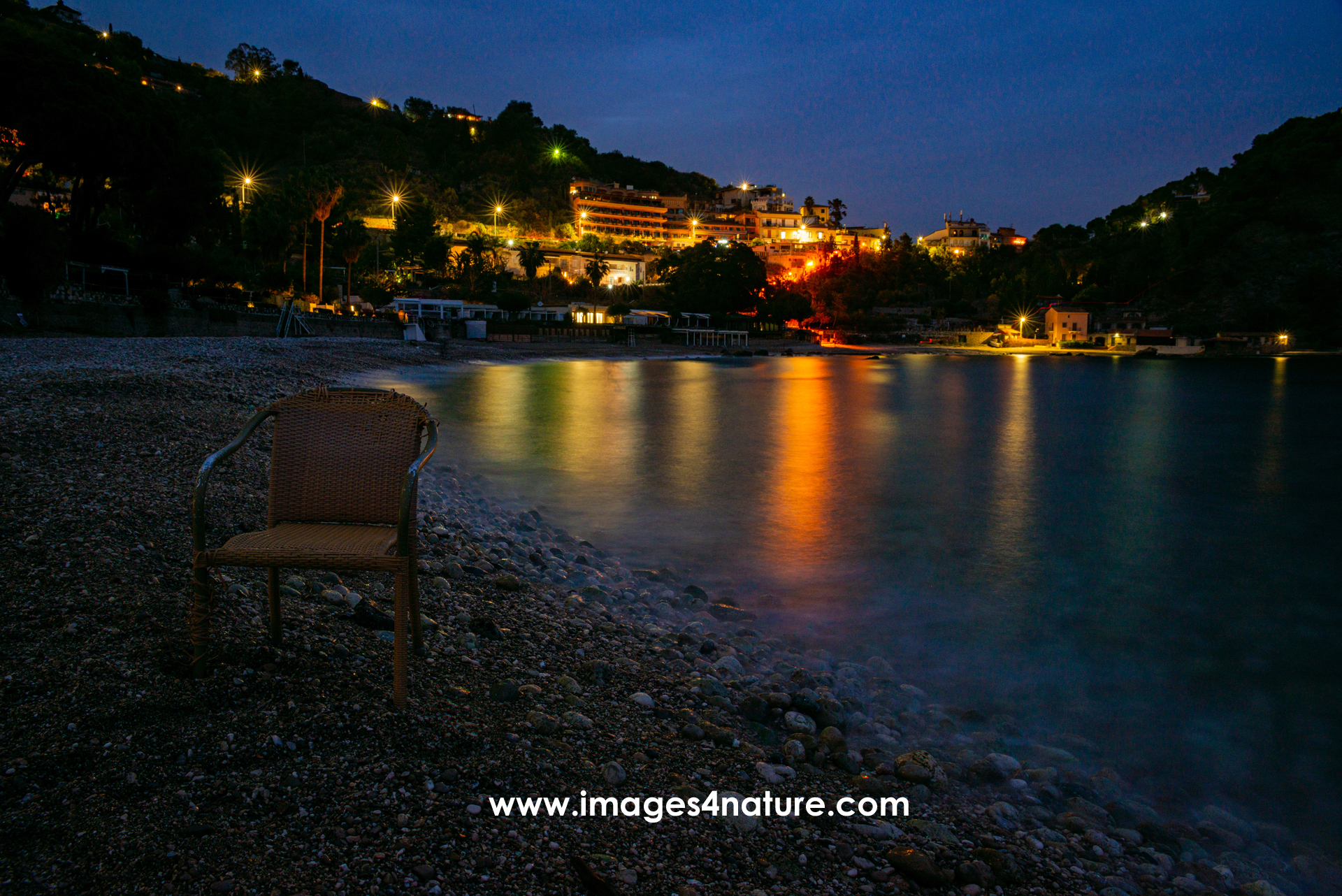 Blue hour view of Mazzaro pepple beach with single chair