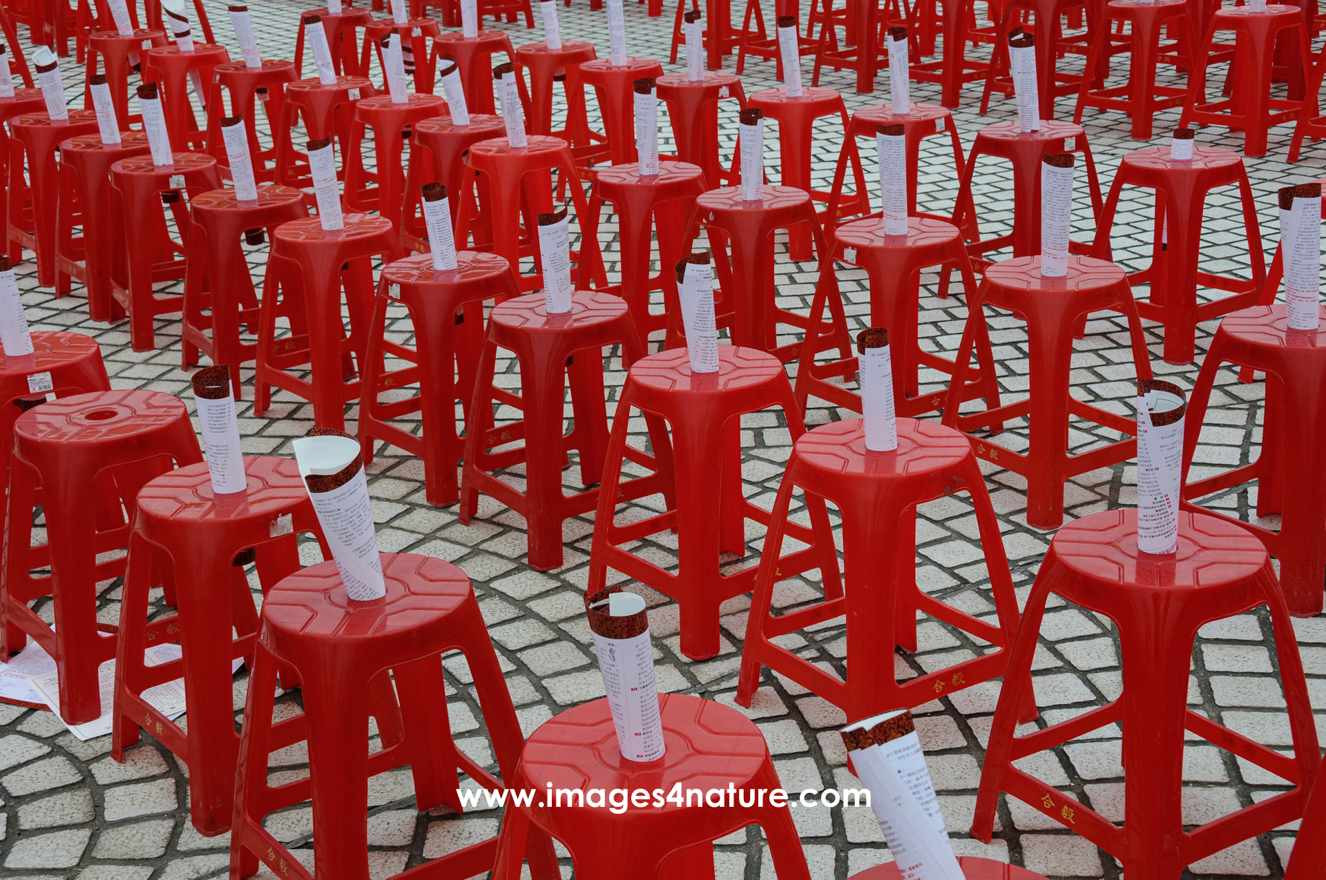 A lot of round red plastic stools perfectly lined up diagonally