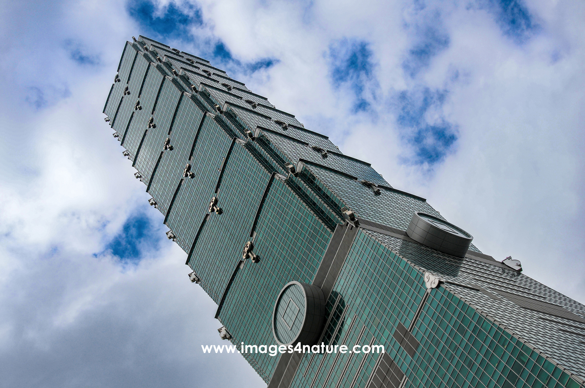 Vertical low angle view of Taipei 101 skyscaper against cloudy sky