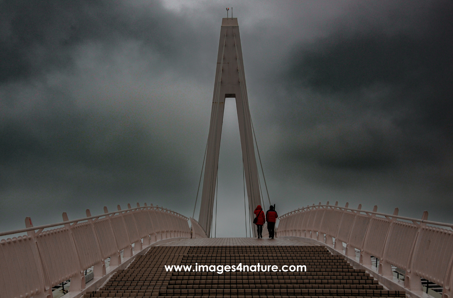 Couple with red rain jackets walking across Lovers Bridge