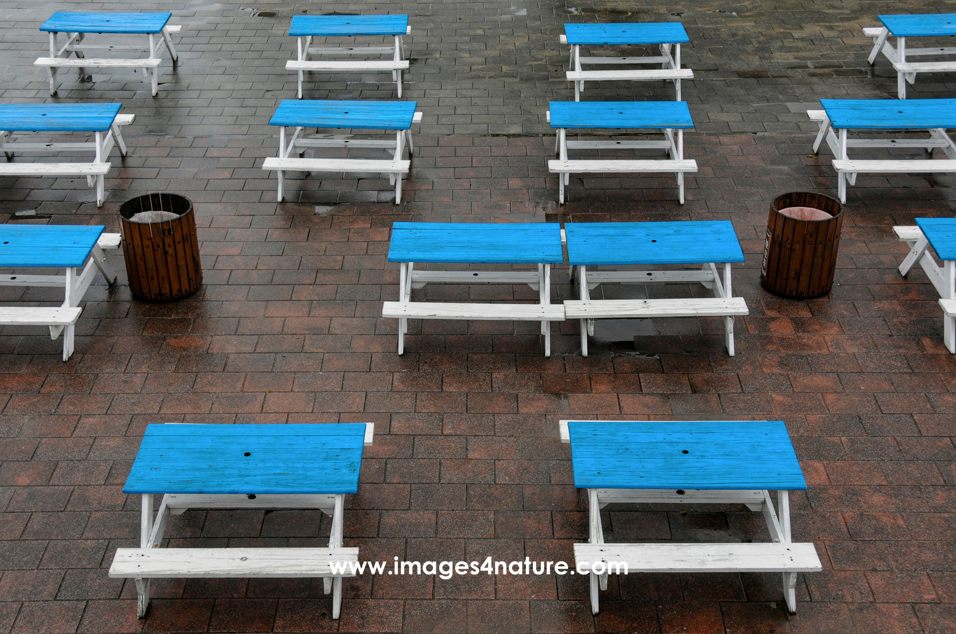 Many blue tables with white benches on red tiled floor