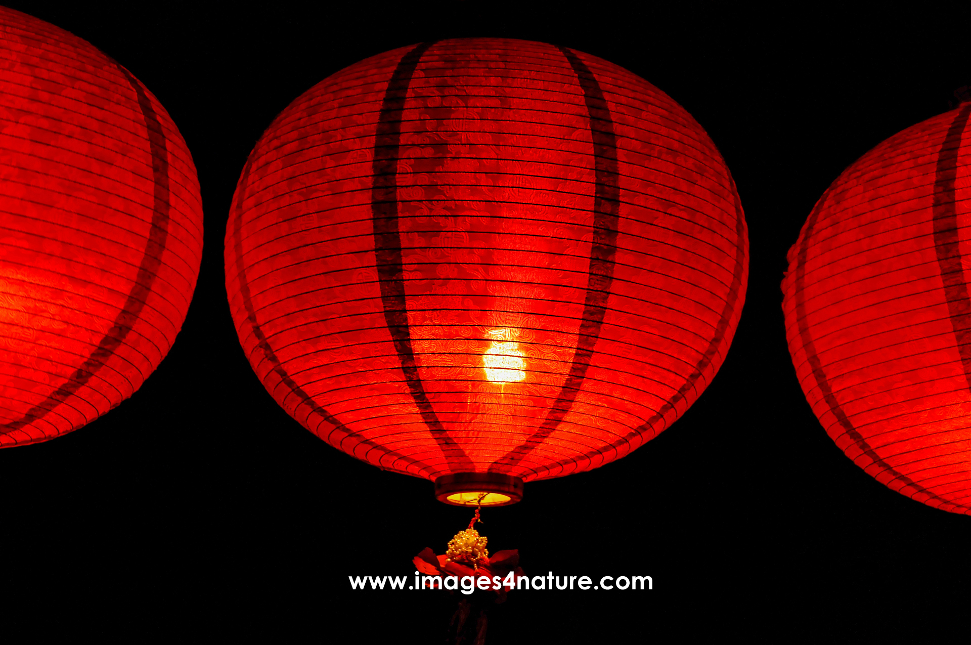 Three glowing red Chinese lanterns at night against dark sky