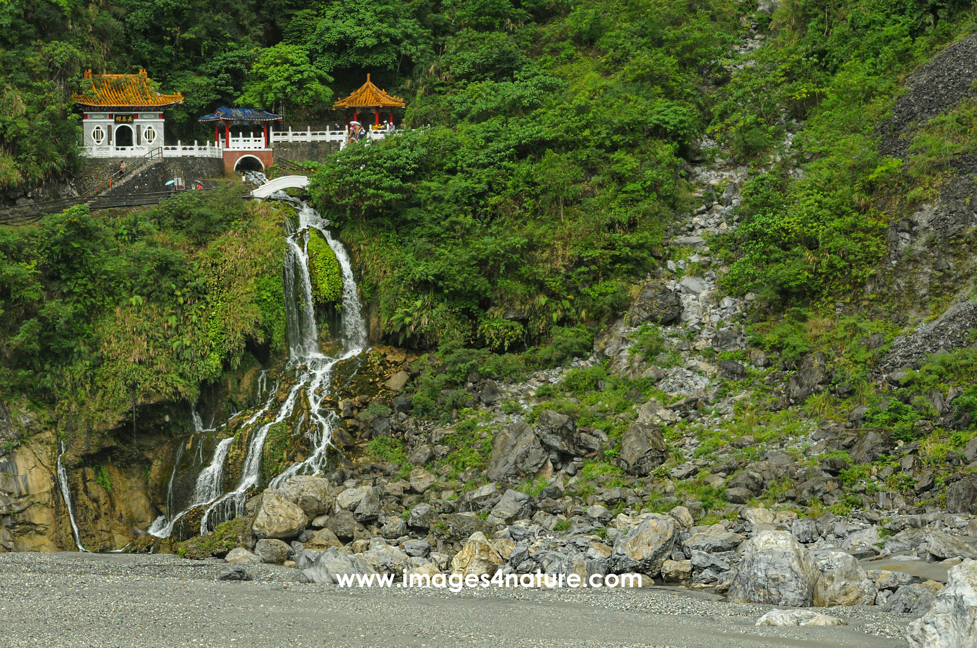 Shrine with waterfall on a steep tree covered mountain slope