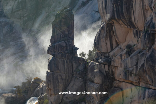 Rock pinnacle with waterfall in a steep gorge of colorful stone