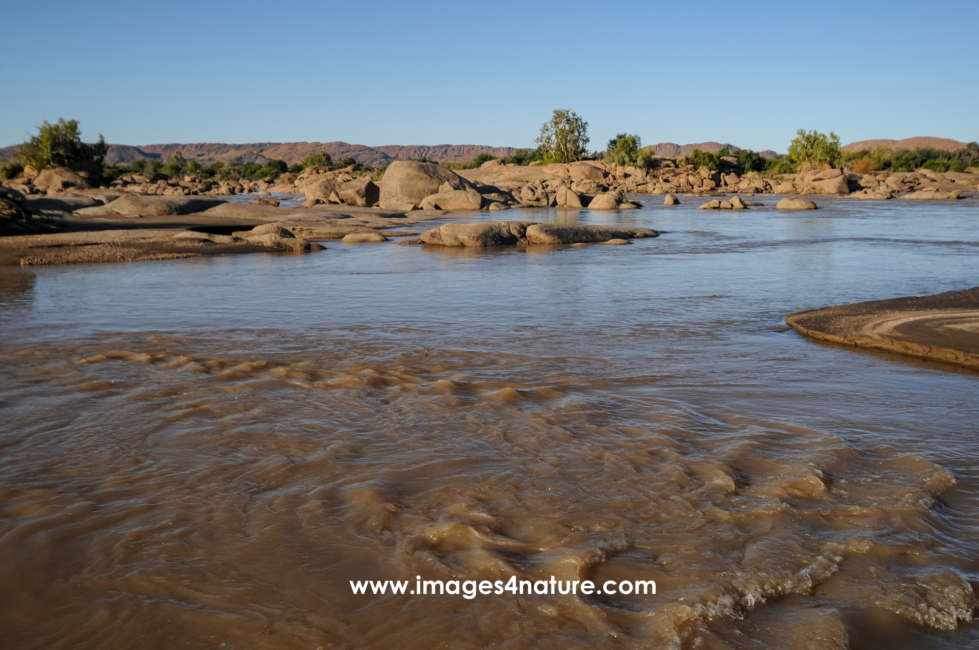 River carrying low water in a dry landscape with many boulders