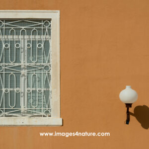 Street lamp and white framed window on an orange wall