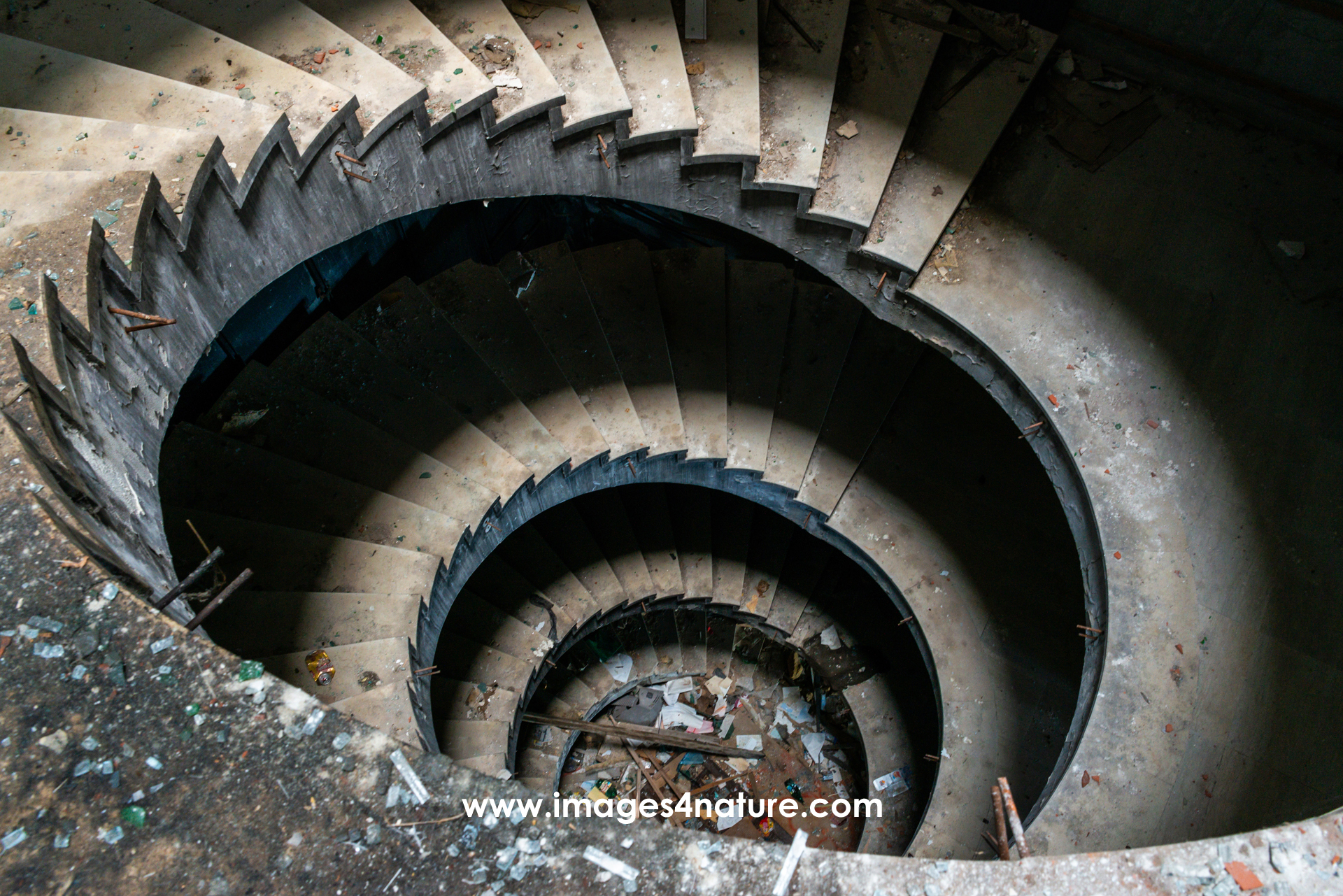 Spiral concrete staircase going down into abandoned hotel