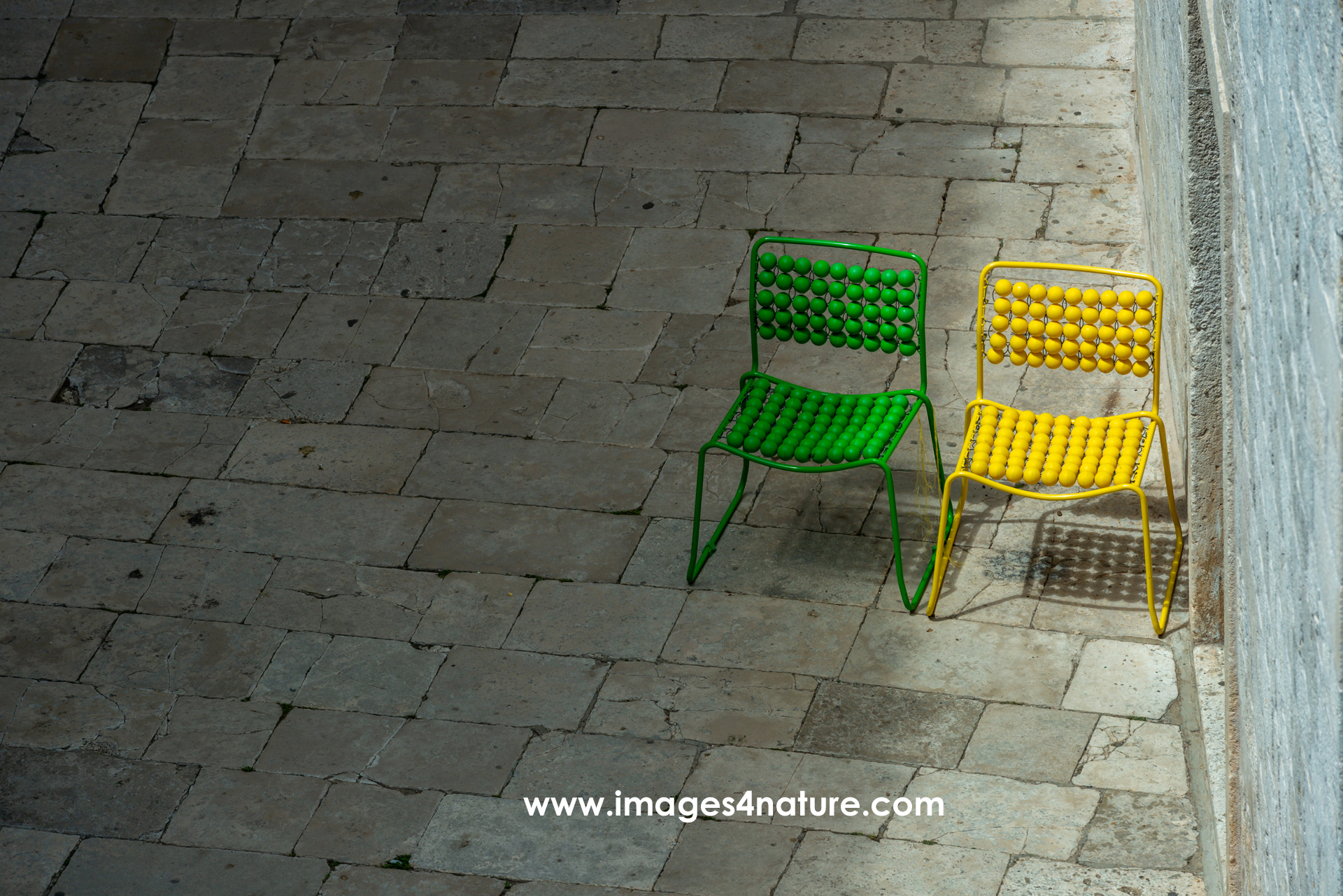 Green and yellow empty chairs on alley with paving stones