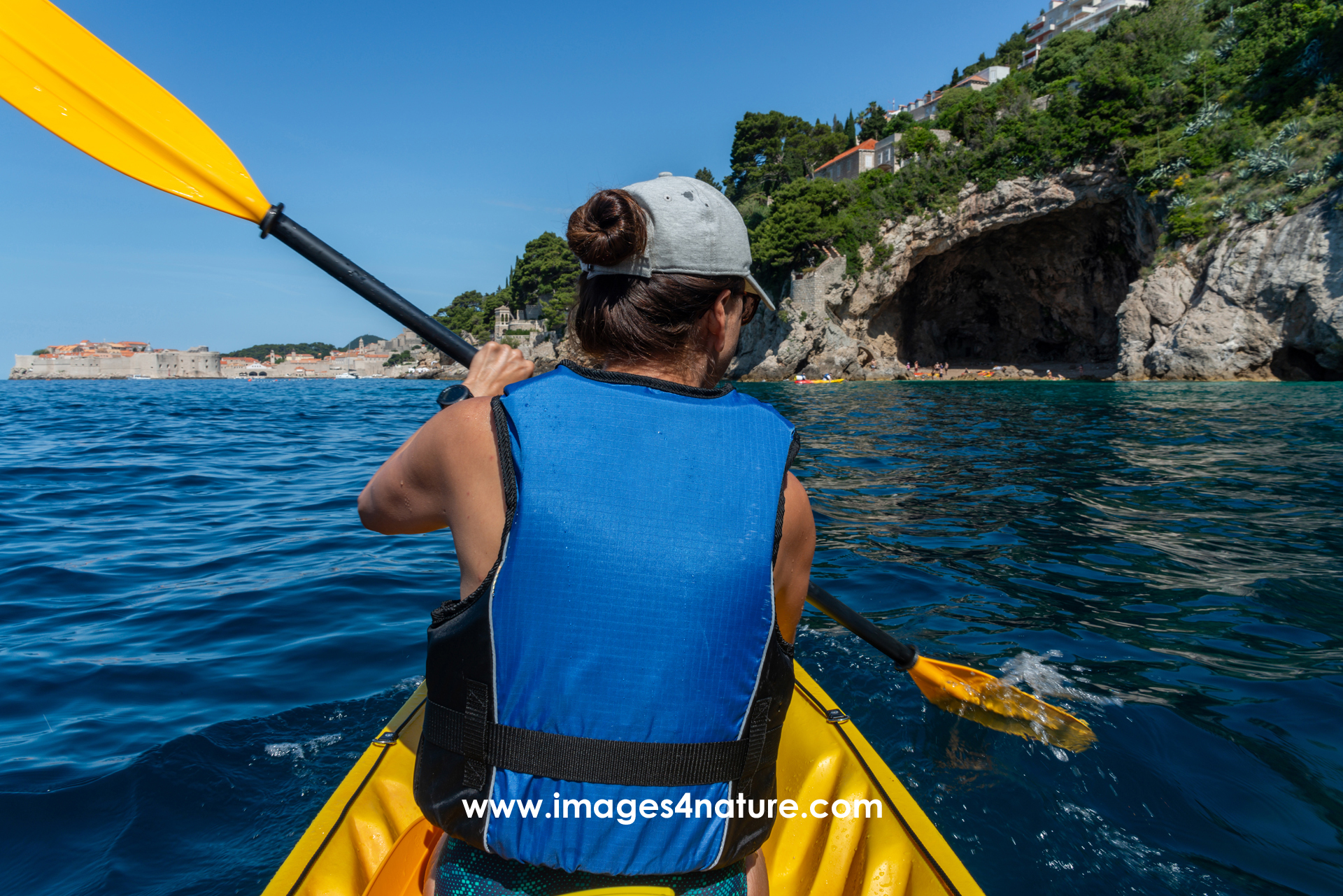 Woman paddling along Dubrovnik coastline in a yellow kayak