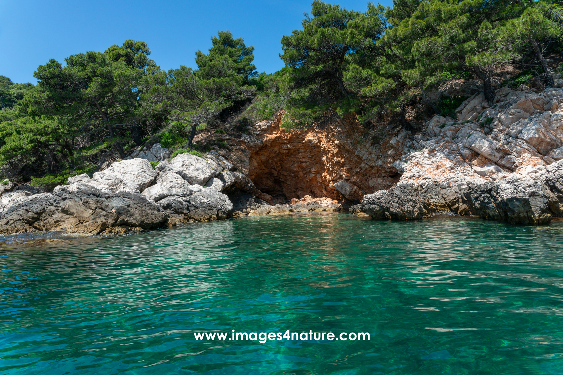 Beautiful coastline with colorful rocks, pine trees and cave