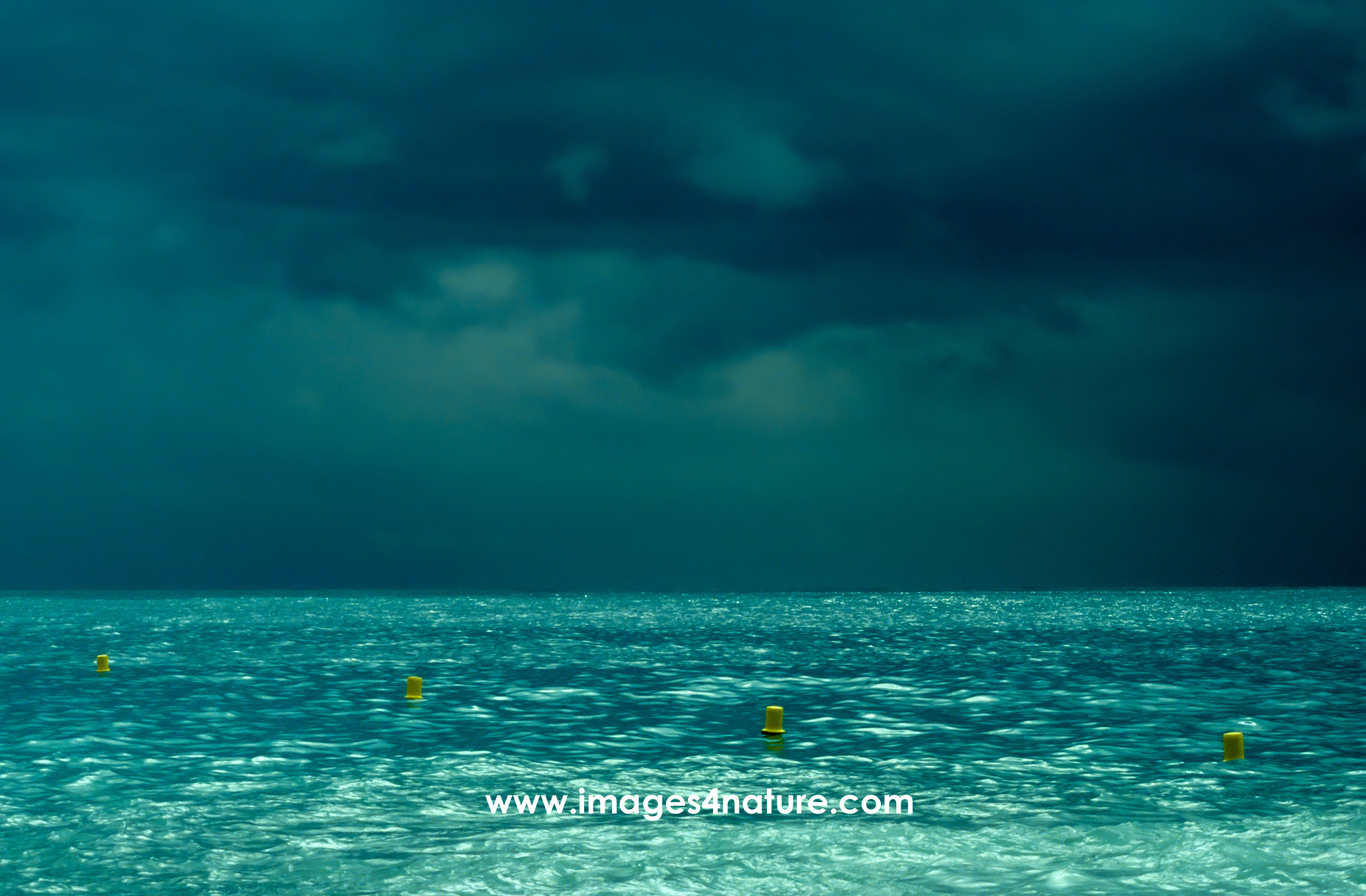 Dark thunderstorm clouds over calm turquoise mediterranean sea