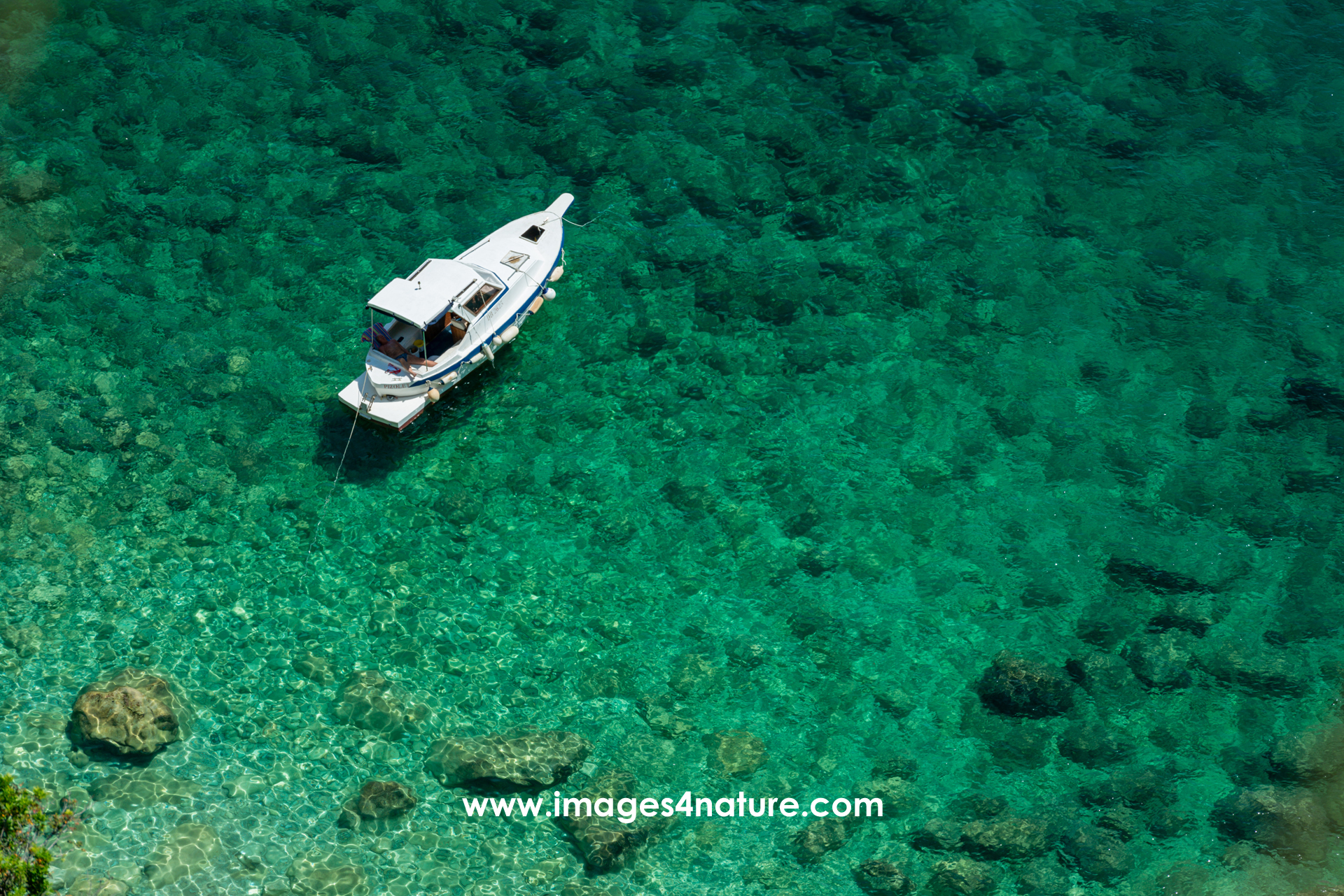 Small boat anchored in peaceful bay with clear turquoise water
