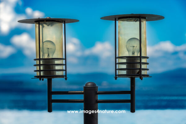 Black metal lamp with two lightbulbs with blue Mediterrenean background