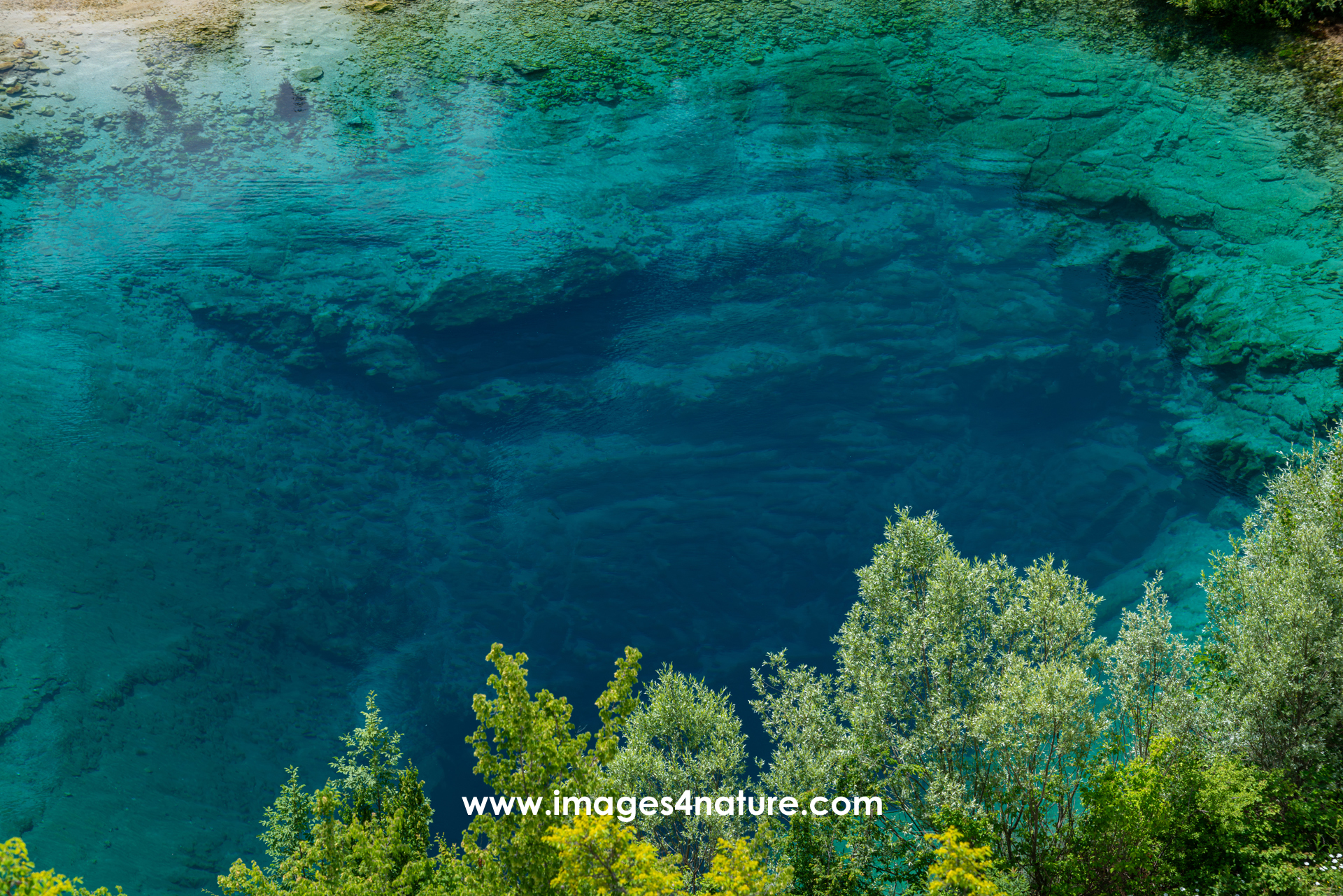 Vertical rock wall at Cetina river source dropping into deep blue water