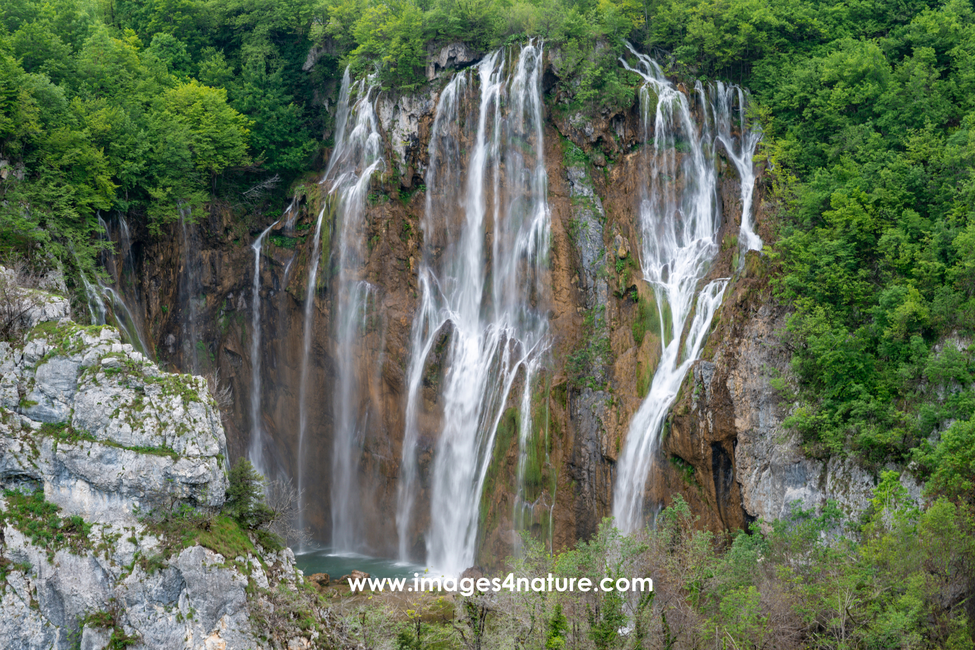 Large scenic Plitvice waterfall dropping into the valley from tree-covered rocks