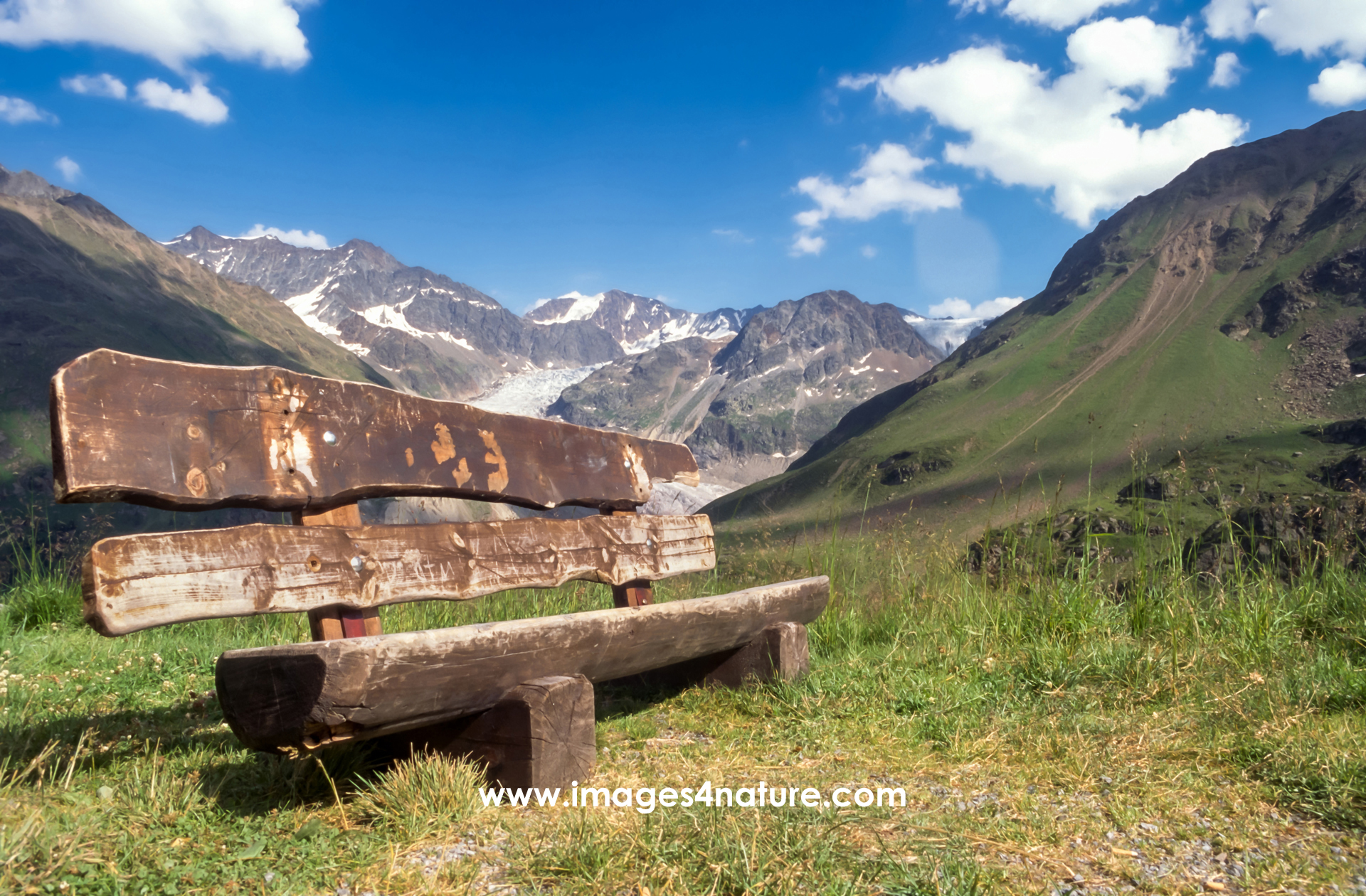Wooden bench on alpine hiking trail inviting to take a rest