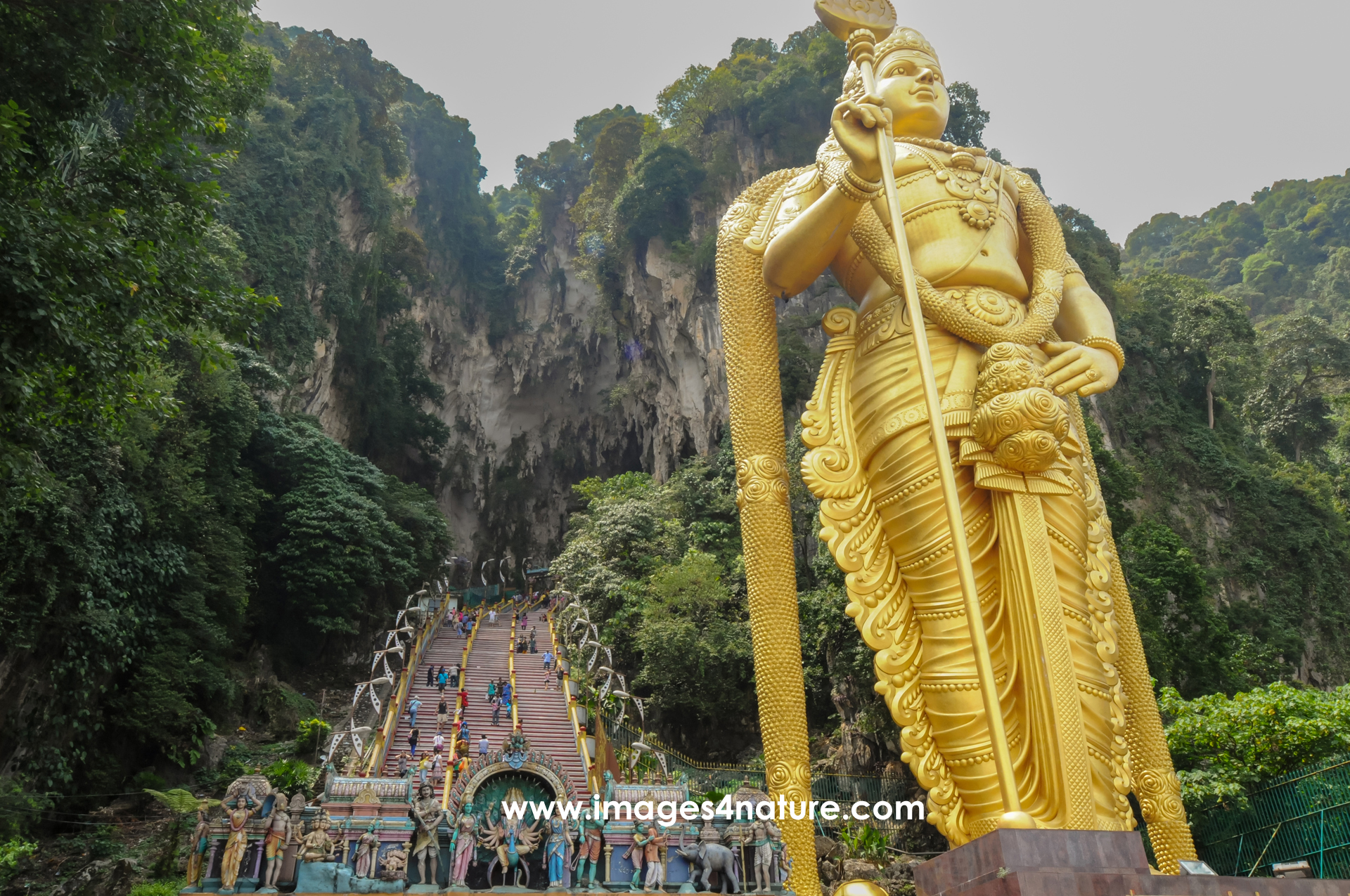 Huge golden statue in front of stairs leading into mountain cave