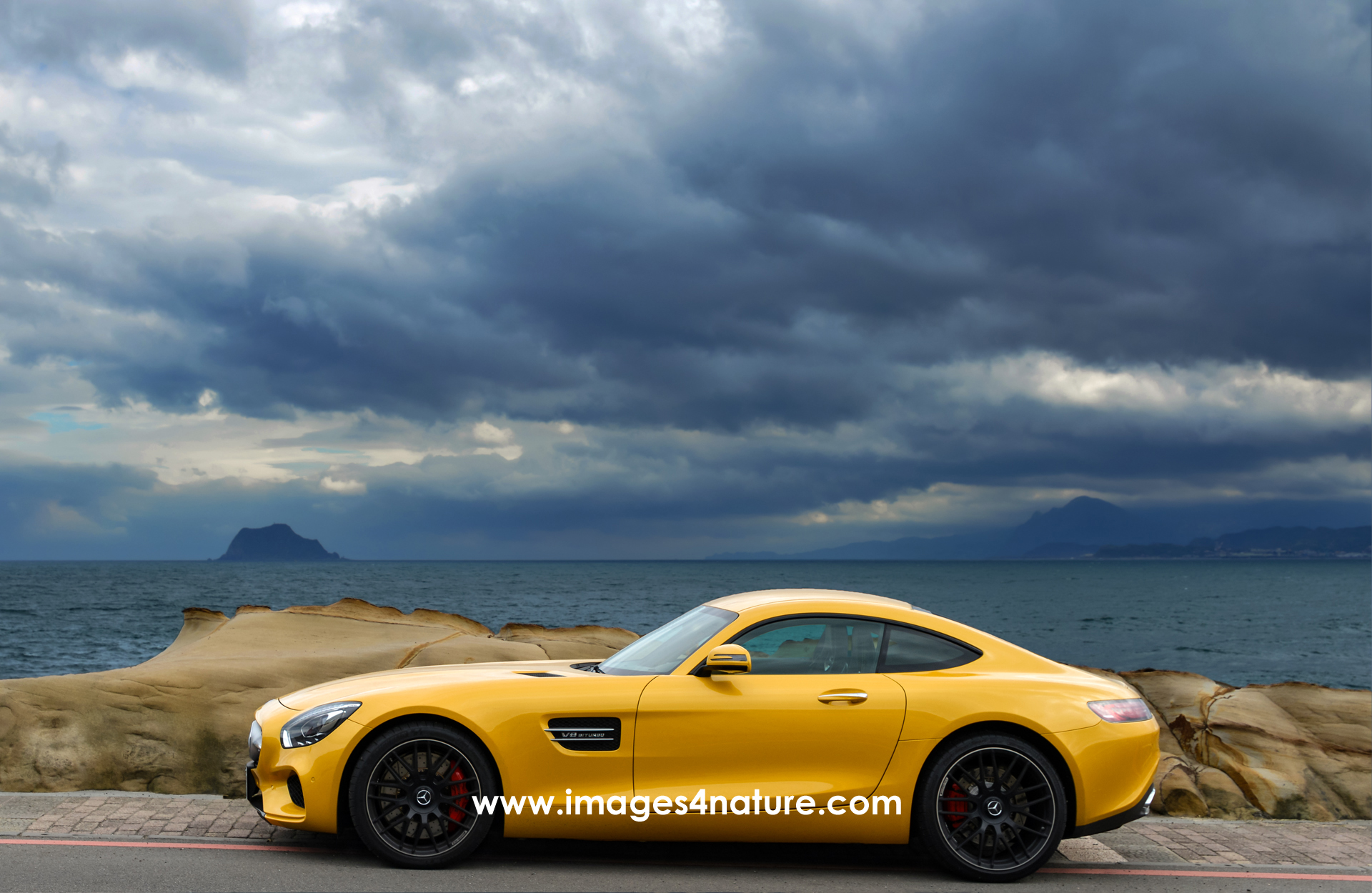 Side view of yellow Mercedes AMG GT Coupe on coastal road