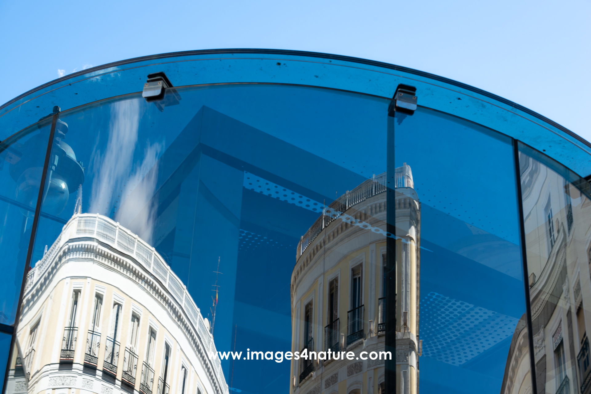 Building tops of Madrid's Puerta del Sol reflecting in a round-shaped glass panel
