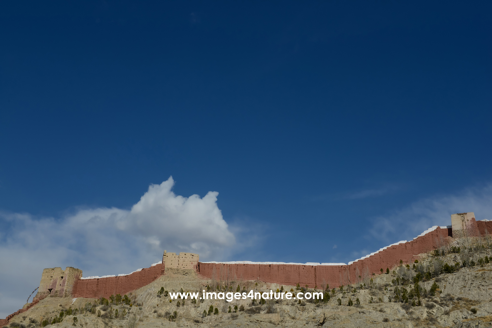 Blue sky with white clouds and the red wall protecting the Palcho Monastery in Gyantse