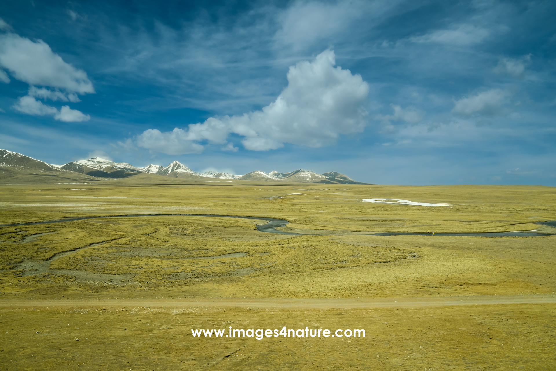 Qinghai-Tibet plateau landscape in winter with grasslands, snow-covered peaks and a river