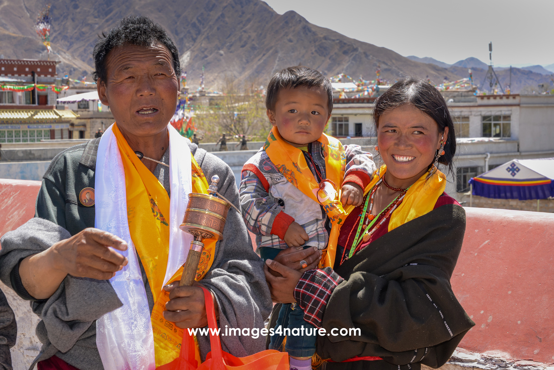 Family picture of Tibetan pilgrim couple with toddler on top of the Jokhang Temple in Lhasa