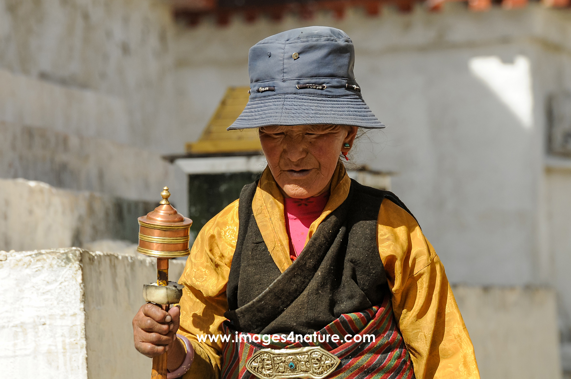 Deeply absorbed Tibetan woman with prayer mill on her pilgrimage inside Tashi Lhumpo monastery