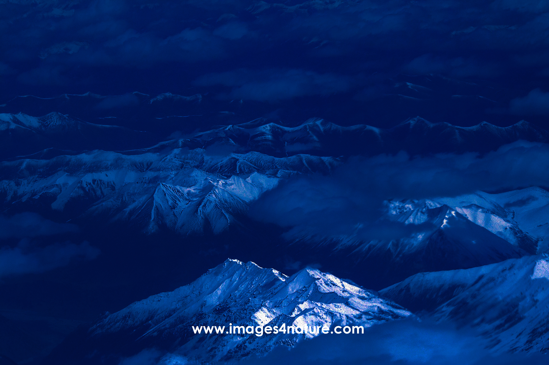Aerial blue hour view of the Himalayas with some peaks illuminated peaks