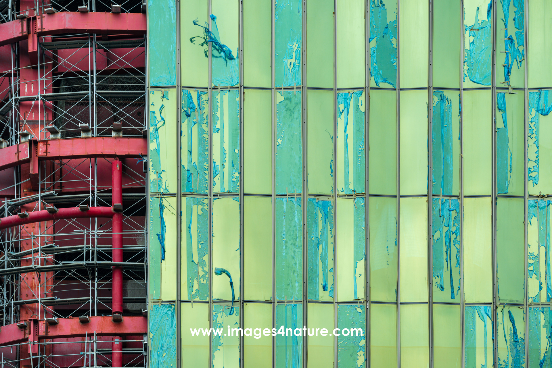 Close-up of the construction site of the Four Seasons Hotel Taipei, with red metal frame on the left, whereas windows covered with green plastic have already been installed on the right.