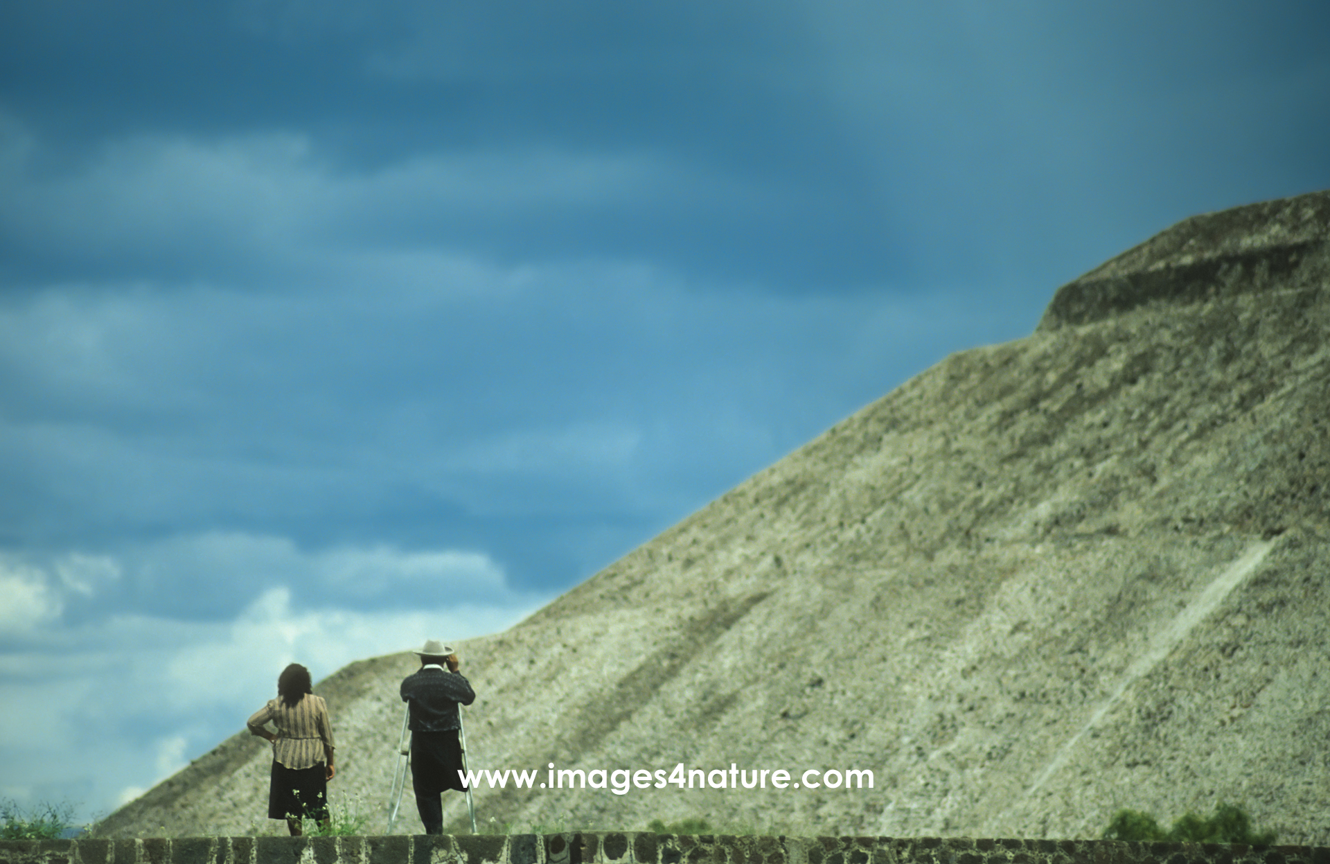 A couple with a man on crutches enjoying the spectacular view of the Pyramid of the Sun at Mexico's Teotihuacán