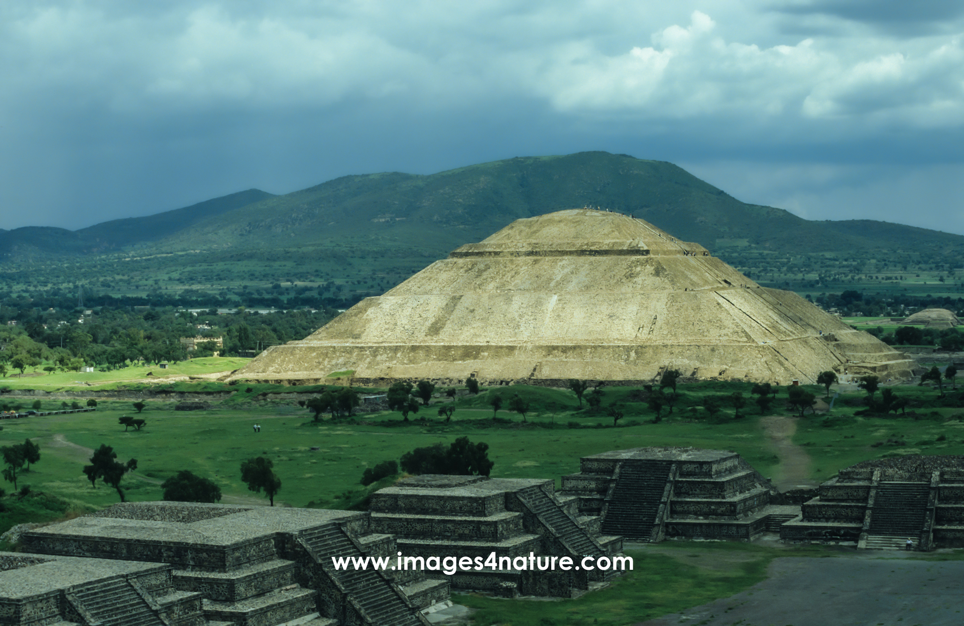 Scenic view of the archeological site of Teotihuacáan on a cloudy day, with the largest pyramid illuminated by the sun