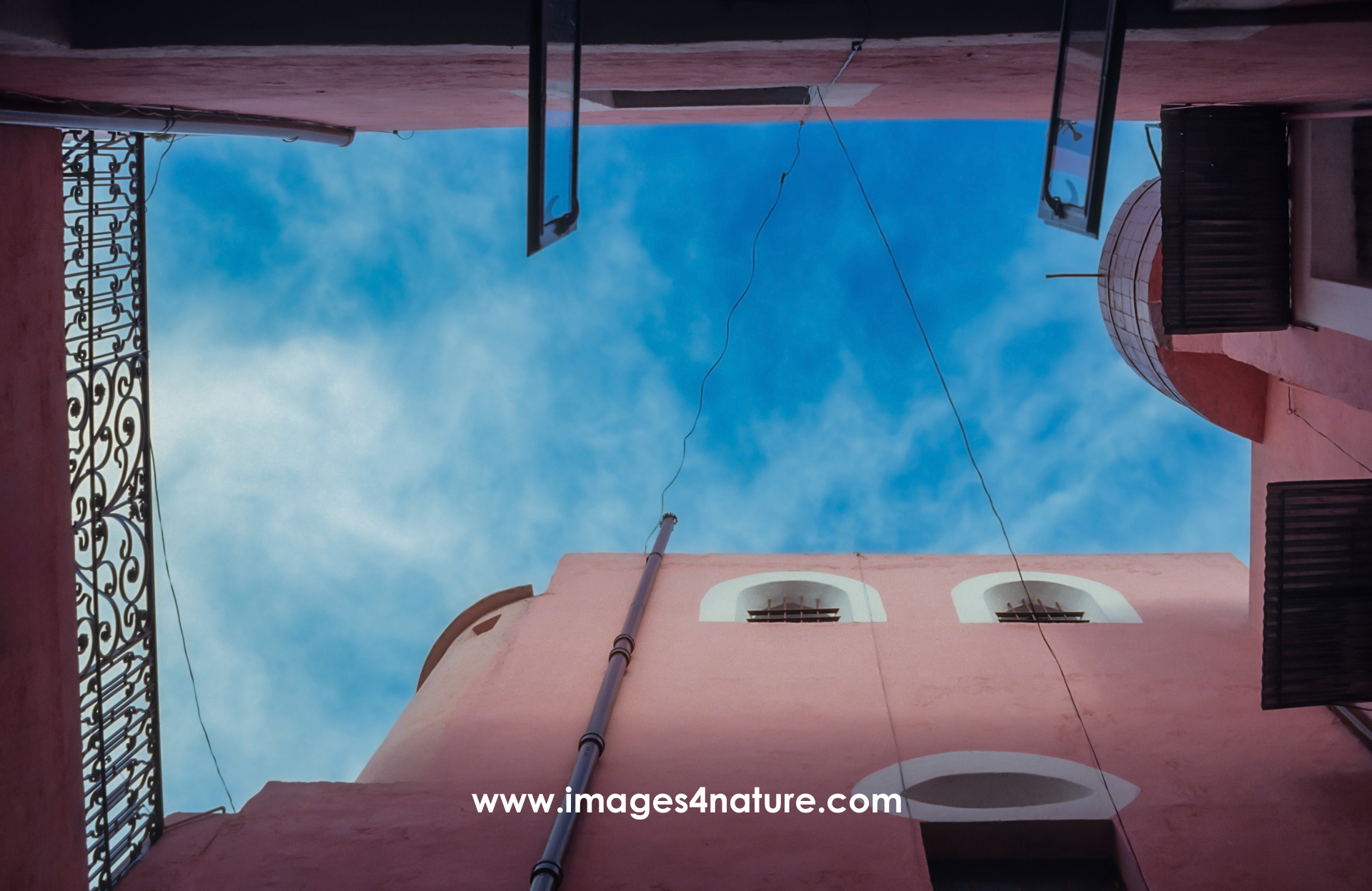 Low-angle view of a inner courtyard of a building painted in pink