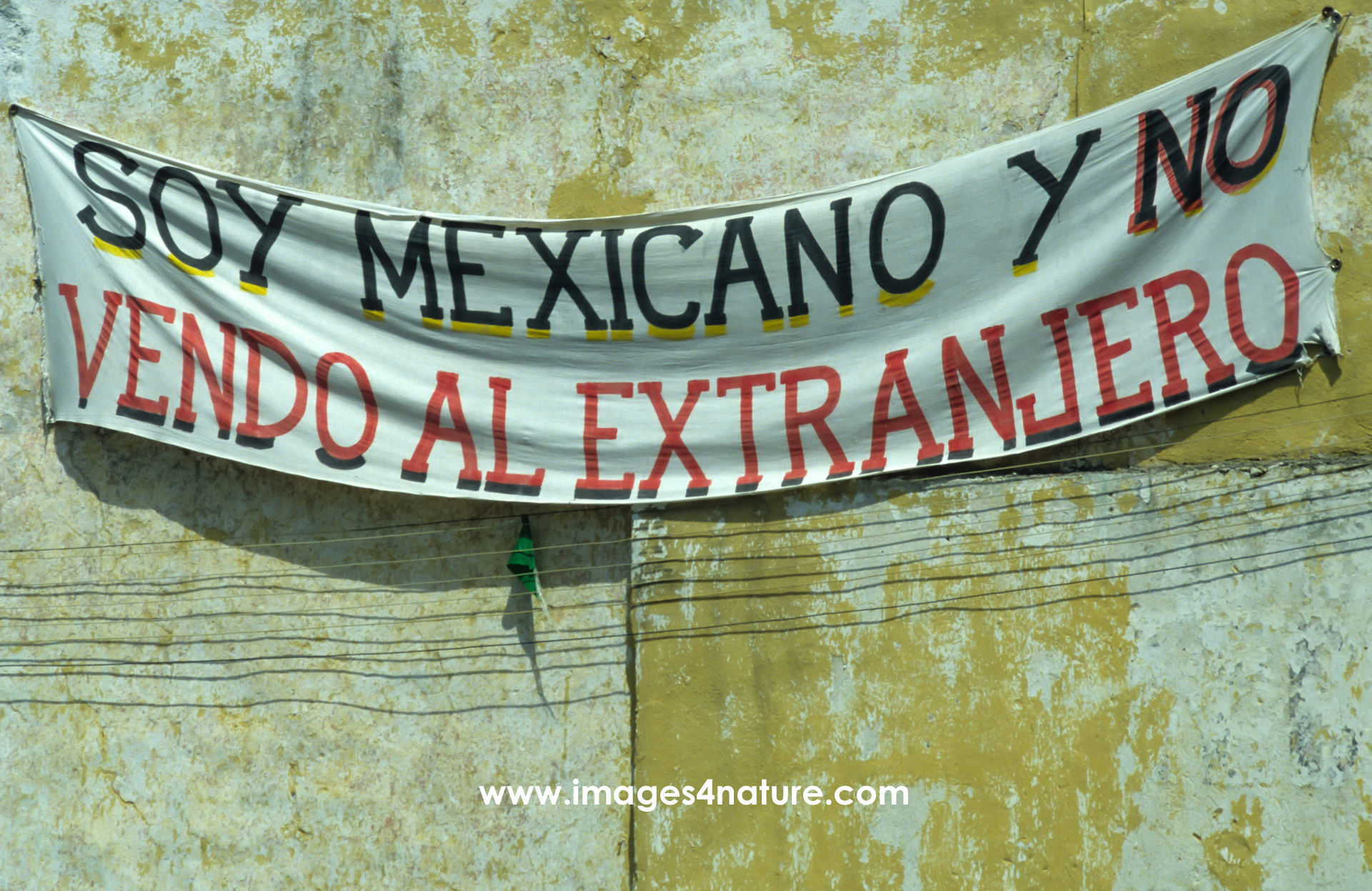 Banner hanging on a weathered wall with protest against real estate sales to foreigners