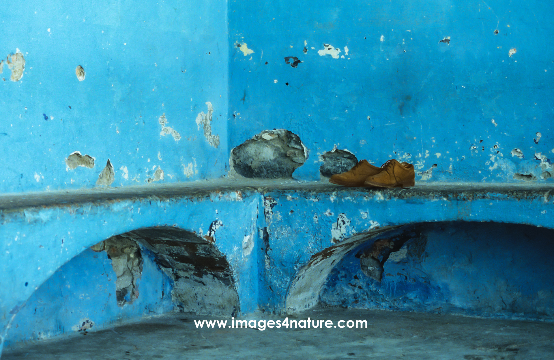 A pair of brown leather shoes on top of arched concrete benches painted in blue