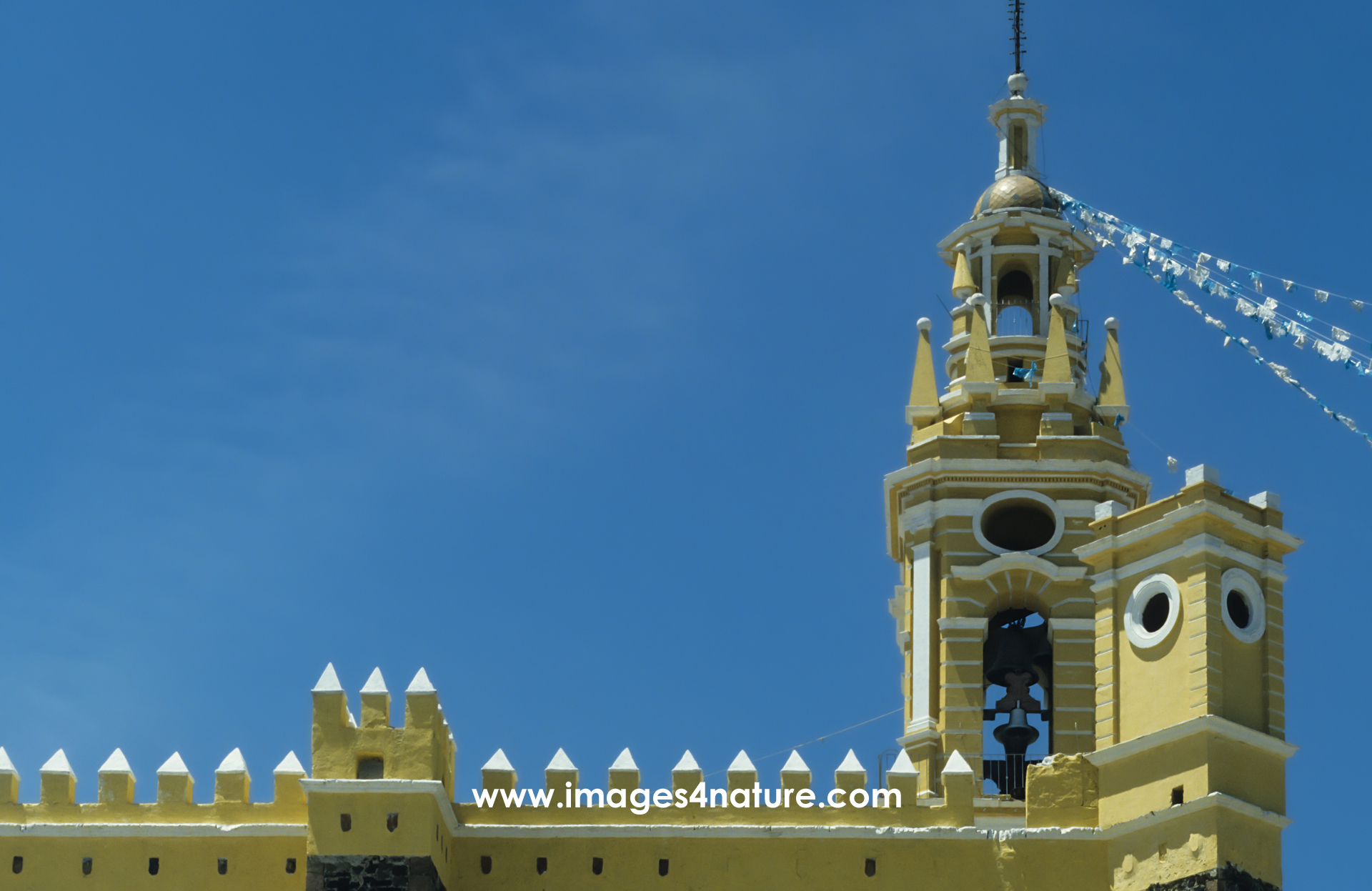 Yellow painted church walls and tower against a dark blue sky