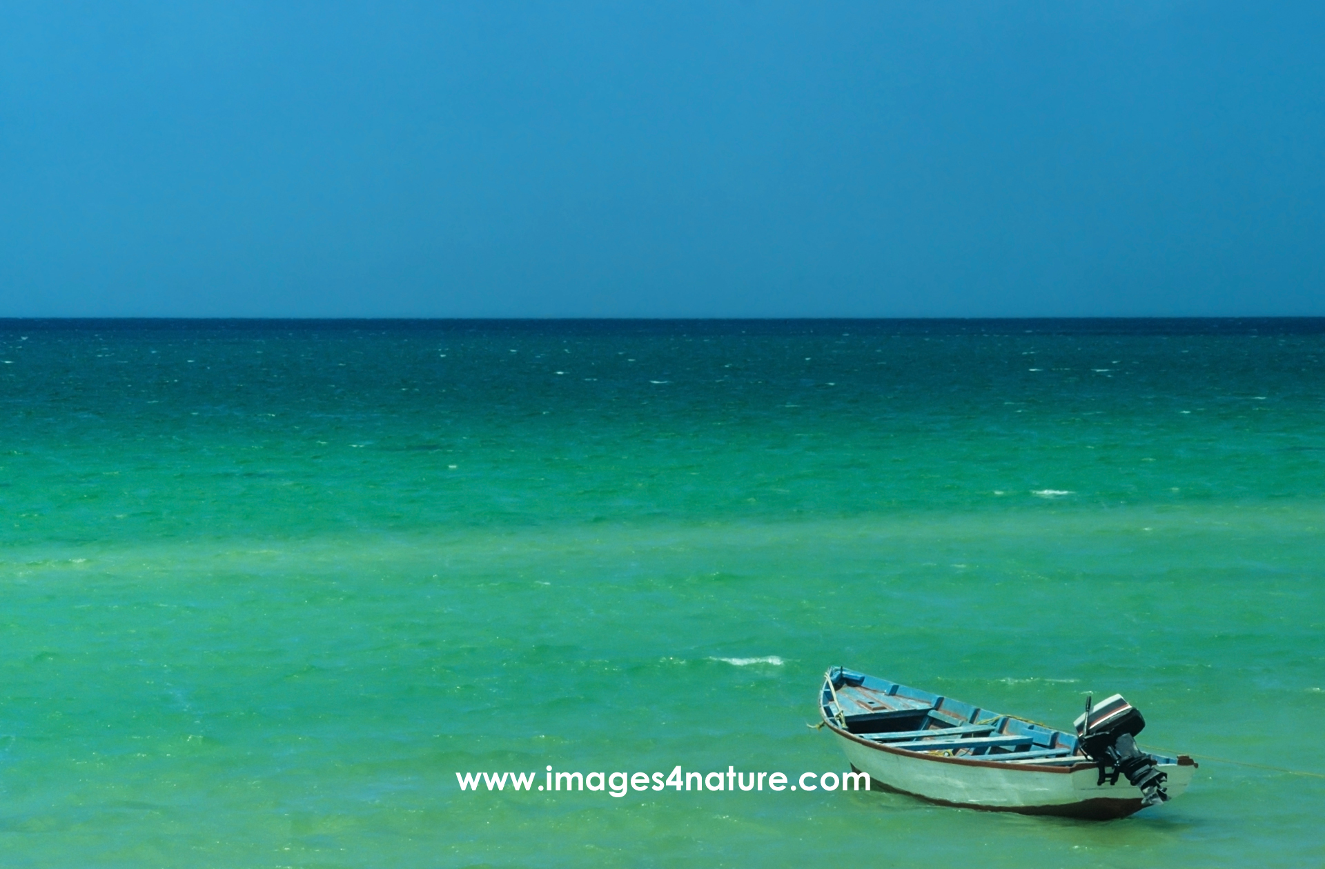 A small boat with outboard motor anchored in the turquoise waters of the Gulf of Mexico