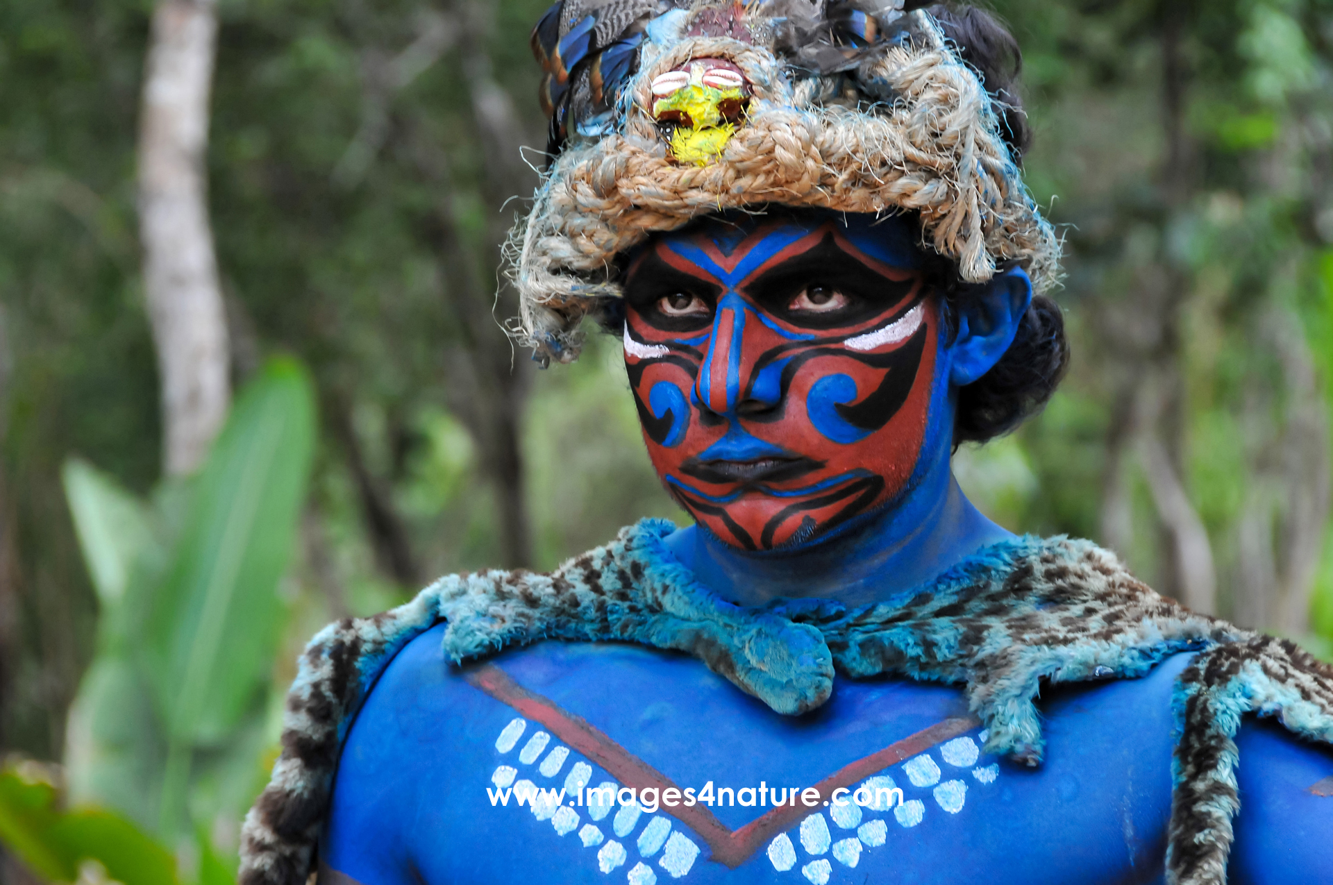 Portrait of a person with traditional Mayan clothes and blue warrior painting